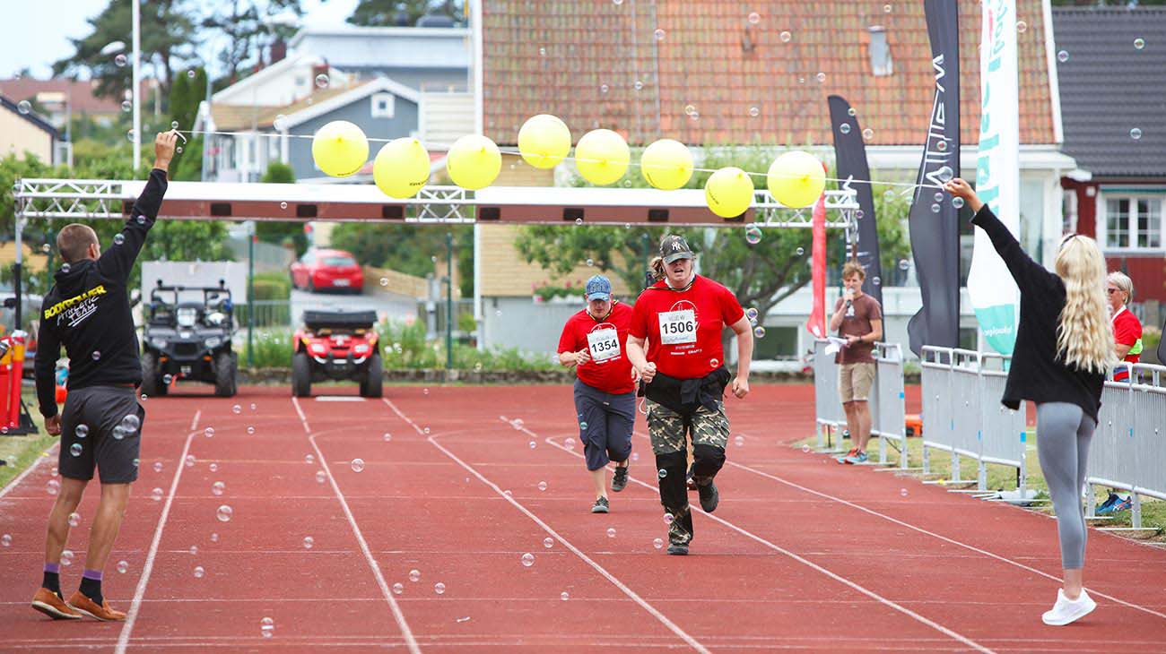 Två personer påväg över mållinjen som består av gula ballonger och såpbubblor.